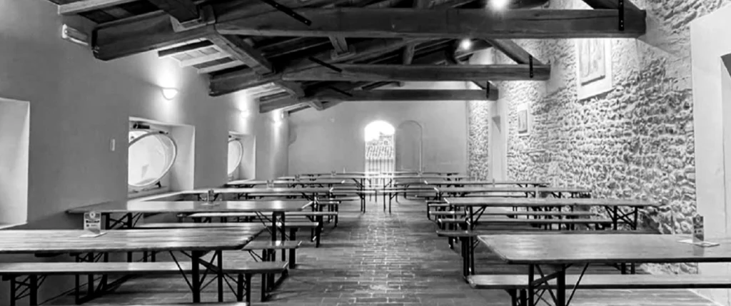 cpv--ambienti-palazzo-mimmi Loggia della Dama di Palazzo Mimmi, ampia sala interna con tavoli, pareti in pietra e travi in legno a vista.